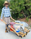 Man in large straw hat pushing a homemade bamboo load-centered wheelbarrow