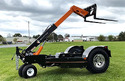 A black & orange Towable Remote-Controlled Fork Lift in a grass field