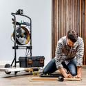 A man on his knees on the floor working with a 5-in-1 Mobile Workshop behind him
